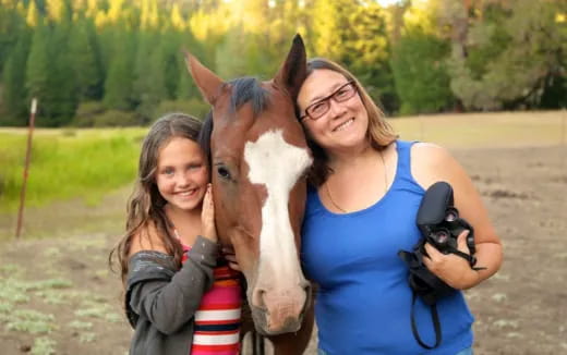 a couple of women posing with a horse