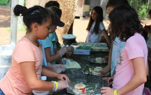 a group of people standing around a table with food on it