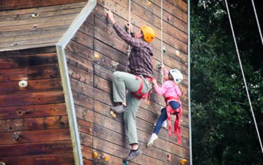 a group of people climbing a wooden wall