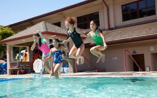 a group of kids jumping into a pool