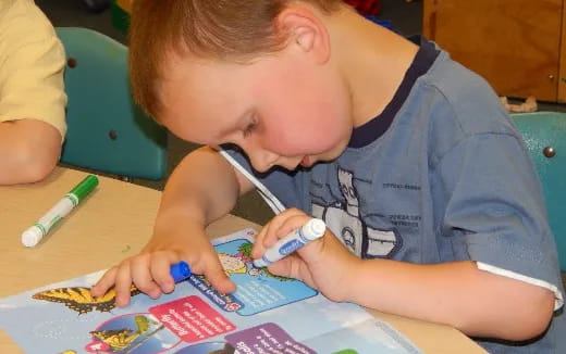 a young boy coloring on a paper