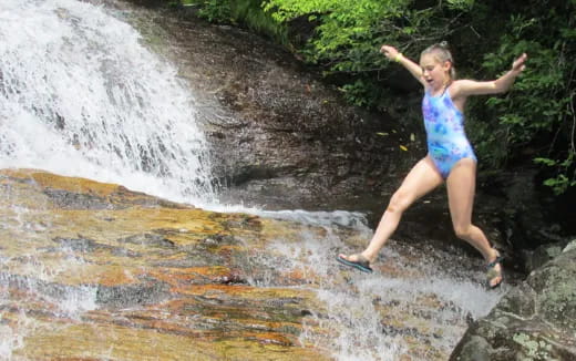 a person in a swimsuit jumping into a waterfall