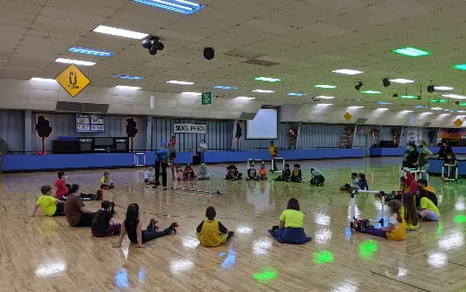 a group of people sitting on the floor in a gym