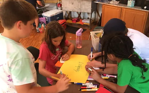 a group of children sitting around a table writing on paper