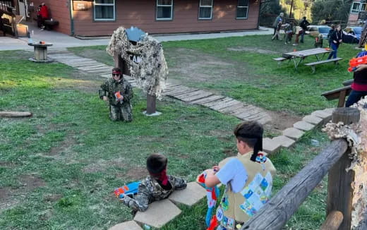 a group of people sitting on a bench in a yard with a statue