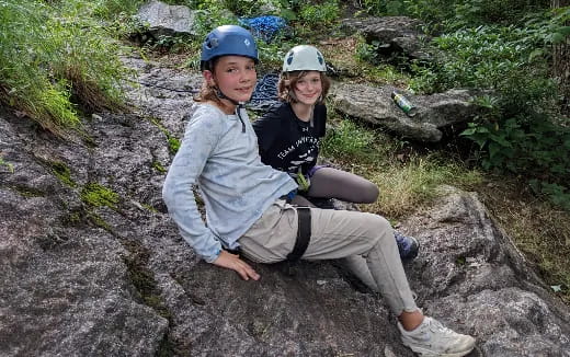a couple of people wearing helmets and sitting on a rock