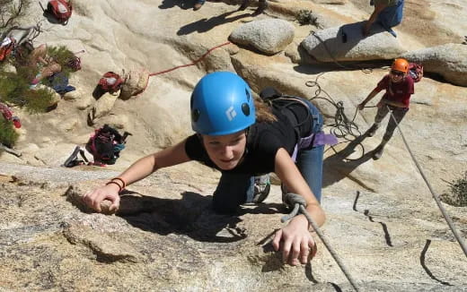a person wearing a helmet and climbing a rock wall