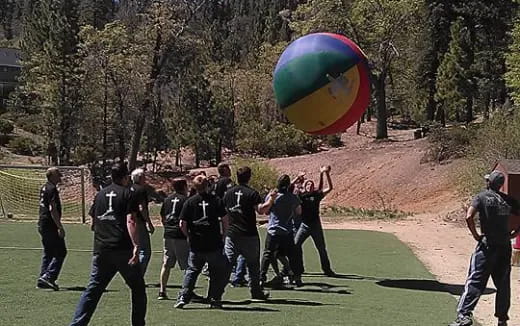 a group of people running with a large balloon
