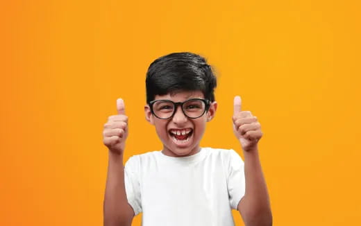 a boy with glasses and a white shirt with his thumbs up