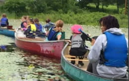 a group of people in a row boat on a river