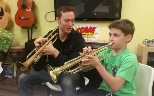 a person playing a trumpet next to a boy playing a guitar