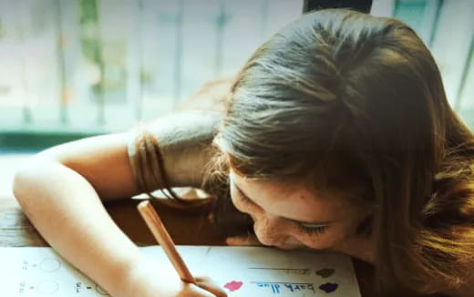 a girl writing on a piece of paper
