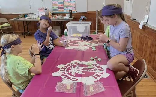 a group of children sitting at a table with a cake