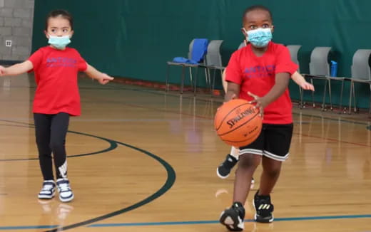 a couple of kids wearing masks and holding a basketball