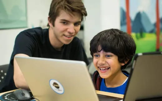 a person and a boy looking at a laptop