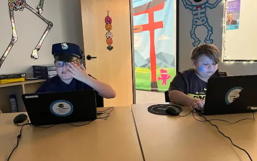 a couple of boys using laptops