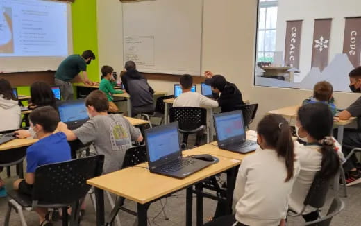 a group of people sitting at desks with laptops