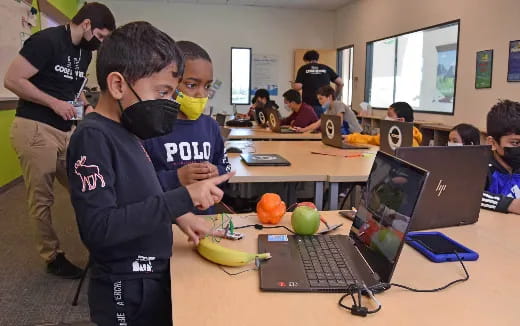 a couple of boys looking at a laptop