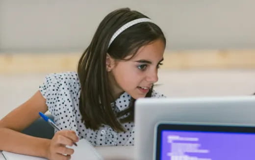 a young girl writing on a computer