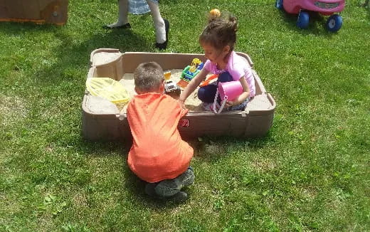 a couple of children playing in a box on grass