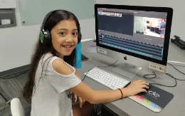 a young girl wearing headphones and sitting at a computer desk
