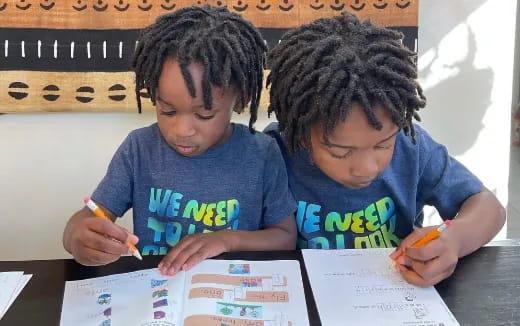 a couple of young boys writing on paper