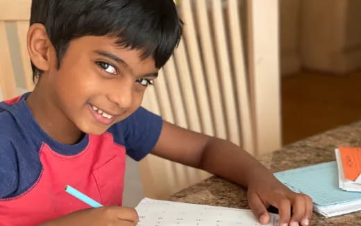 a young boy writing on a piece of paper