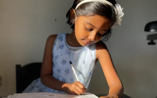 a young girl writing on a piece of paper