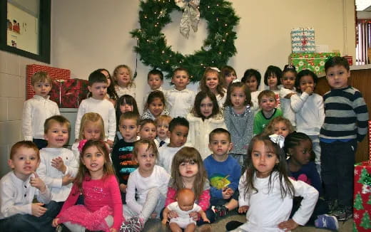 a group of children posing for a photo in front of a christmas tree