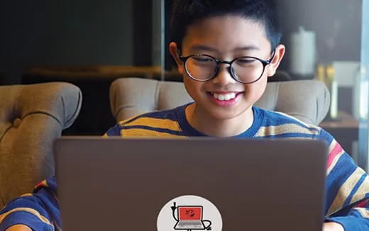 a boy wearing glasses and looking at a laptop