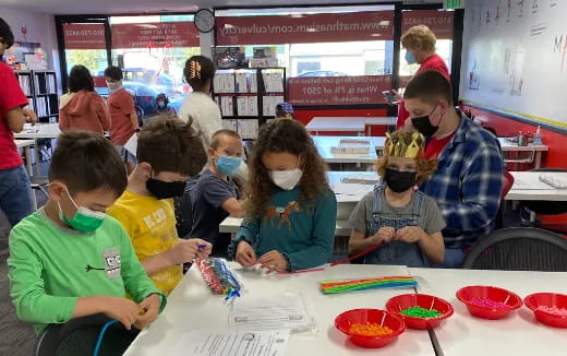 a group of people sitting at a table with a child wearing a mask