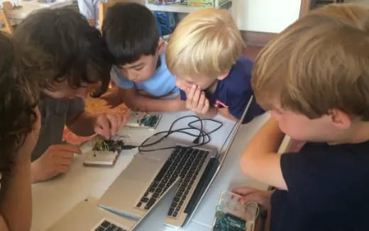 a group of children looking at a laptop