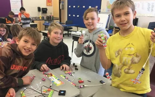 a group of children sitting at a table with a toy