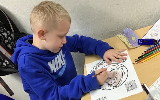 a child sitting at a desk writing on a book