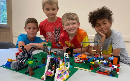 a group of boys sitting at a table with a toy building