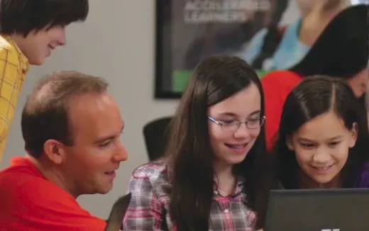 a group of people looking at a laptop