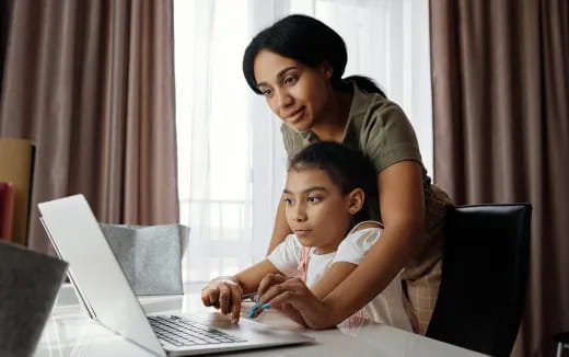 a person and a child looking at a laptop