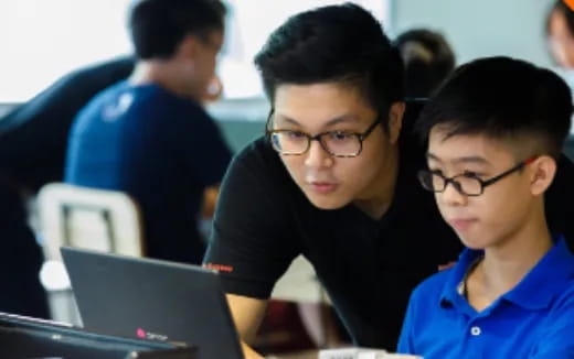 a few young boys looking at a laptop