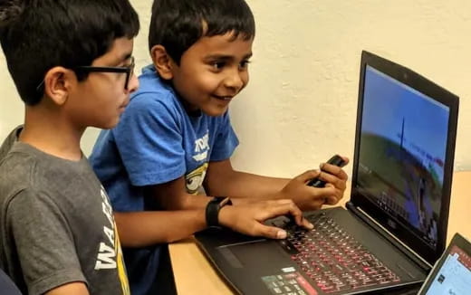 a couple of boys looking at a computer screen