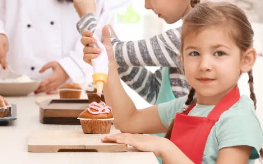 a young girl making a cupcake