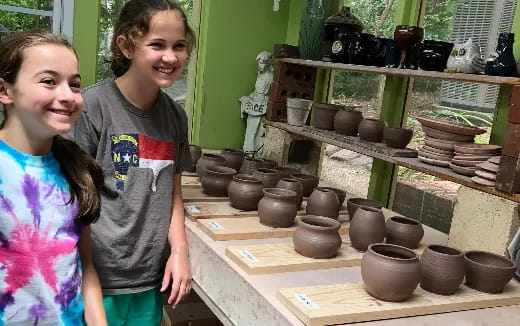 a couple of children standing next to a display of pottery