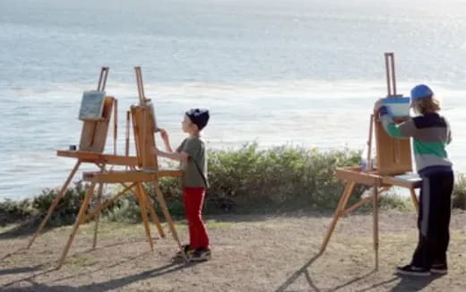 a person and a child painting on a beach