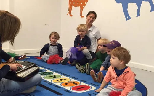 a group of children sitting on the floor playing a piano