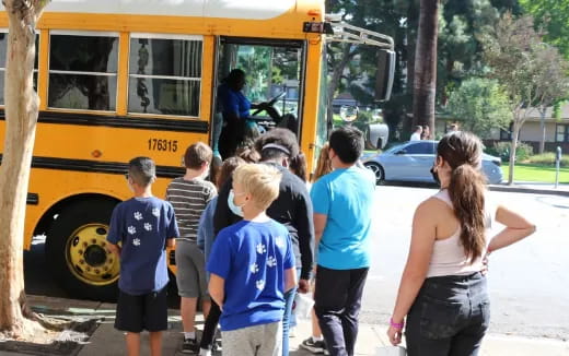 a group of people standing next to a school bus