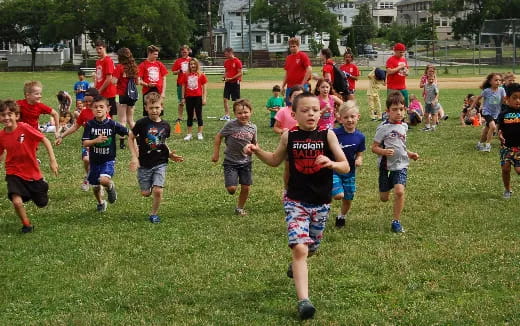 a group of children running on a grass field