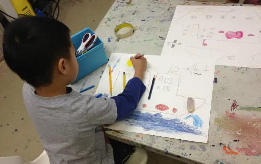 a young boy painting on a white board