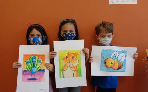 a group of children holding up drawings