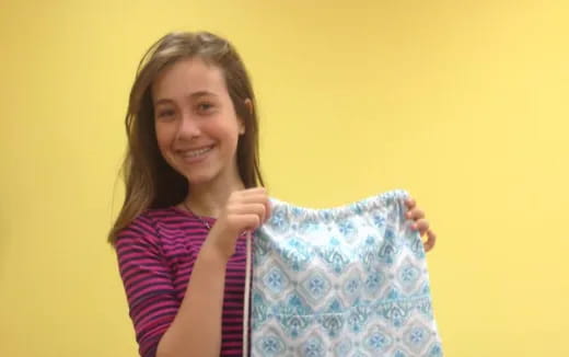 a person smiling and holding a striped pillow