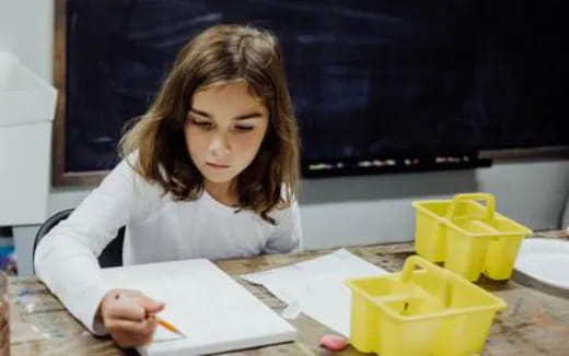 a woman sitting at a table writing on a piece of paper