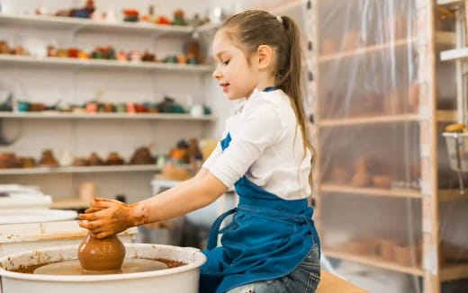 a young girl holding a clay pot